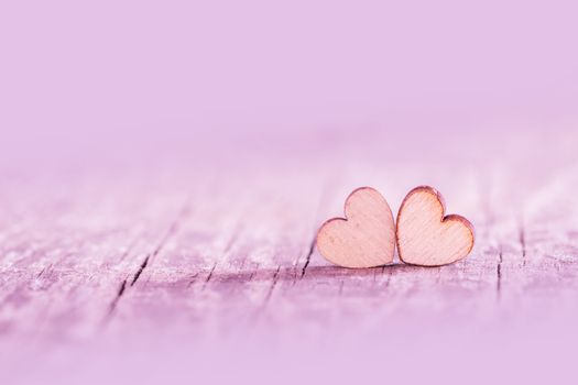 Two small wooden pink hearts on old cracked wood background