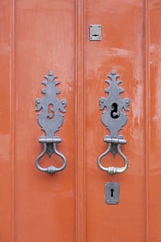 Old red wooden door, detail of a red painted decoration and door security