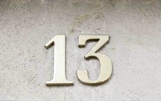 Number thirteen on a wall, detail of house numbers on figures