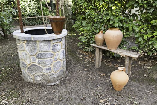 Well in a garden detail of a rural garden with a water well and jugs