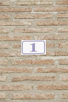 Number one in a brick wall, detail of a number on a wall in a house, information