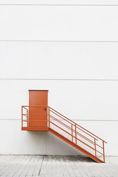 Red metal staircase on the outside, detail of a red painted ladder, urban decoration