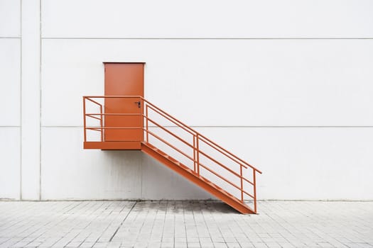 Red metal staircase on the outside, detail of a red painted ladder, urban decoration