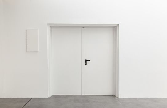 White door on a new white room, detail of the interior of a new building, modern architecture and