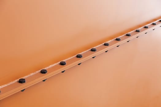 Red metal wall with screws, detail of modern architecture, construction and decoration