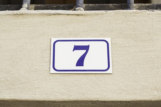 Number seven on a wall, detail of a wall with an information number, odd number
