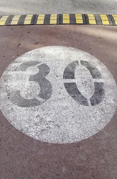 Traffic sign on asphalt, painted number thirty on the ground, speed limit sign. precaution and safety