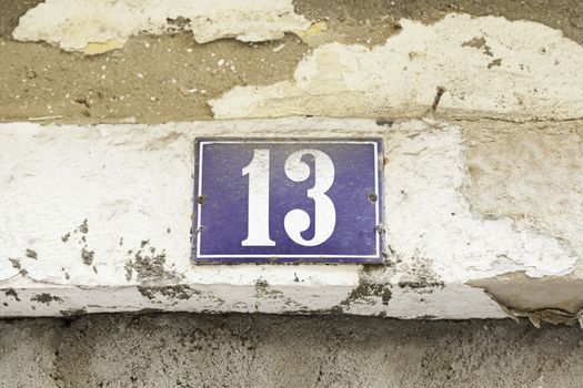 Number thirteen on a wall, detail of a number of information in a house