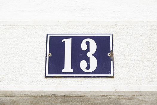 Number thirteen on a wall in a house, detail of a wall with a figure on a plate 