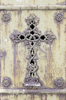 Old rusty metal cross, detail of an old cross on a metal wall, cemetery