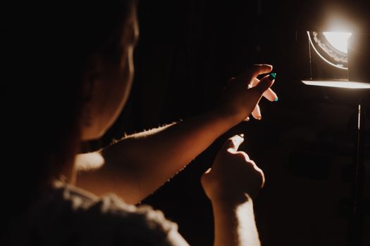 girl reaching for the light of the lantern, wooman in a dark room. illuminated hands with spotlight