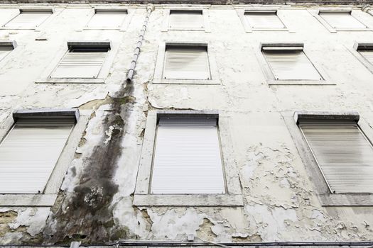 Old abandoned and battered facade detail of a dirty wall and ruinous