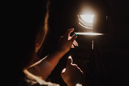 girl reaching for the light of the lantern, wooman in a dark room. illuminated hands with spotlight