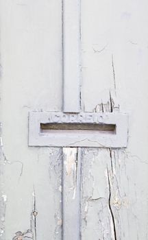 Abandoned gray wooden door with mailbox, detail of an old door damaged on the street