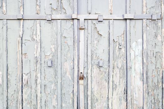 Abandoned gray wooden door, detail of an old door damaged on the street