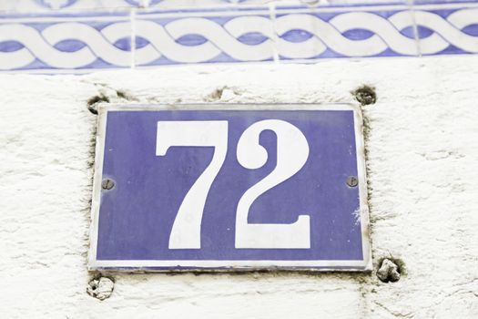 Number seventy-two on a wall, detail of a number of information on a plate in a house