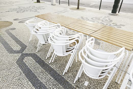 Deck chairs on the street, detail of chairs and tables of a bar in a city street