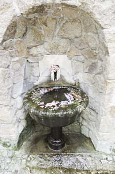 Old stone fountain with flowers, detail of a decorated stone sculpture, ancient atrte