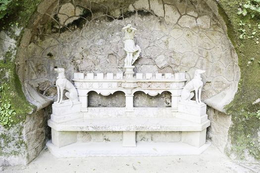 Detail of a stone bench with statues, ancient art in a garden of Portugal