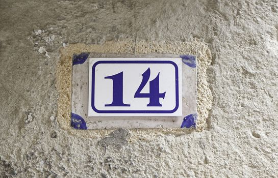 Number fourteen on a wall, detail of a number on the wall of a house, information number, even number