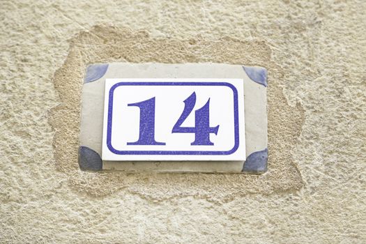 Number fourteen on a wall, detail of a number on the wall of a house, information number, even number