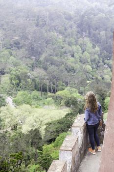 Girl looking at the landscape in a castle, detail of a young woman in an old castle