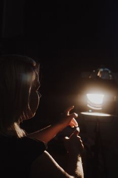 girl reaching for the light of the lantern, wooman in a dark room. illuminated hands with spotlight