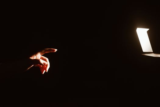 girl reaching for the light of the lantern, wooman in a dark room. illuminated hands with spotlight