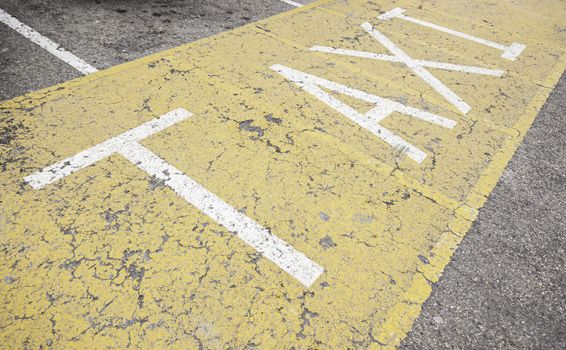 Taxi sign on asphalt, painted detail of a yellow road sign and safety information