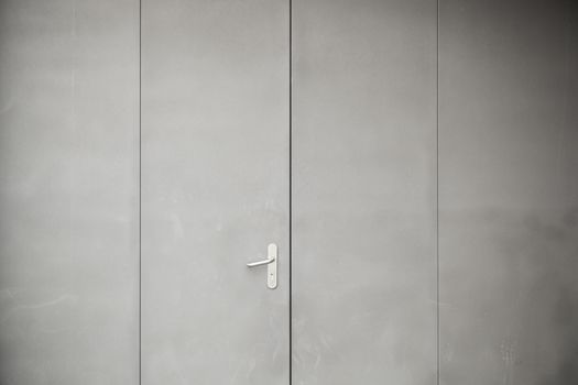 Gray metal door, detail of a closed metal door painted gray steel background texture