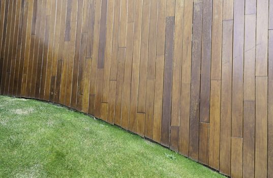 Wooden wall with grass, detail of a wall lined with wooden flooring grass, urban garden