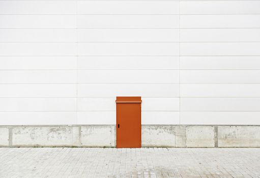 Red door in a wall, detail of a wall in an industrial building, closed, safety and security