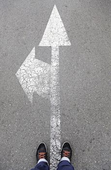 Directional arrow on the asphalt with a few feet, detail of a direction sign painted on the asphalt road safety