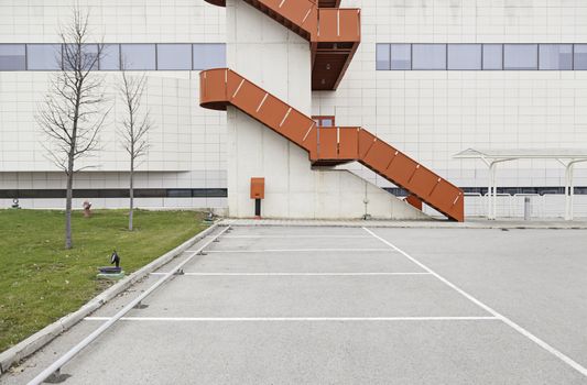 Building facade with red staircase, detail of a wall in the parking lot outside, architecture