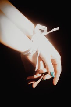 tied hands with ribbon isolated on black background highlighted with light