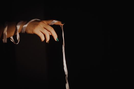 tied hands with ribbon isolated on black background highlighted with light