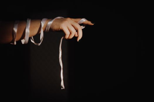 tied hands with ribbon isolated on black background highlighted with light