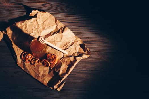 Honey with wooden honey dipper and fruits on wooden table close up