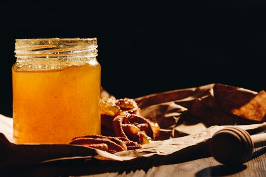 Honey with wooden honey dipper and fruits on wooden table close up