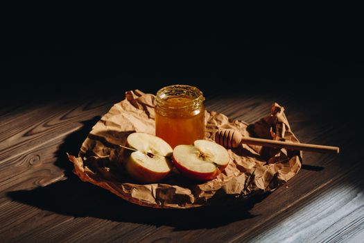 Honey with wooden honey dipper and fruits on wooden table close up