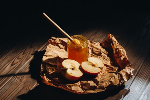 Honey with wooden honey dipper and fruits on wooden table close up