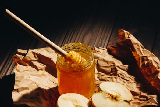 Honey with wooden honey dipper and fruits on wooden table close up