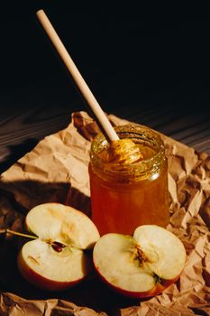 Honey with wooden honey dipper and fruits on wooden table close up