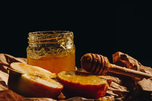 Honey with wooden honey dipper and fruits on wooden table close up