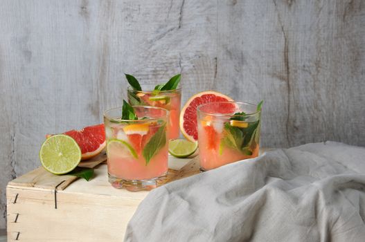 Cocktail of juice squeezed red grapefruit and leaves of delicate lemon basil, lime slices and chilled ice cubes. 