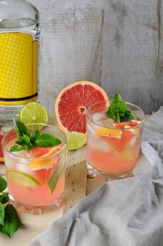  Cocktail from London dry gin with juice from squeezed red grapefruit and leaves of delicate basil of lemon, lime slices and chilled ice cubes.