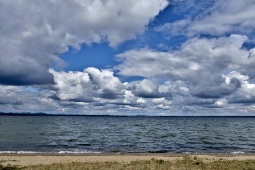 day lake in gray-white cloudy weather, South Ural, Uvildy, in the distance are seen the Ural mountains