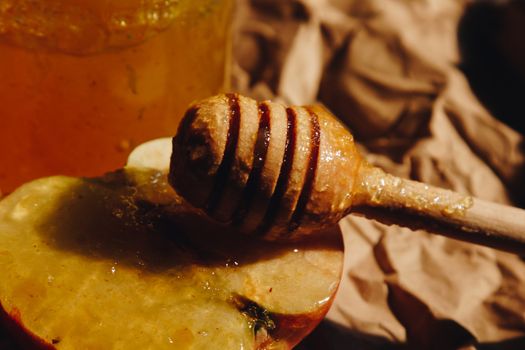 Honey with wooden honey dipper and fruits on wooden table close up