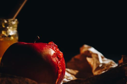 Honey with wooden honey dipper and fruits on wooden table close up