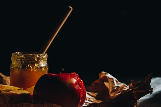 Honey with wooden honey dipper and fruits on wooden table close up